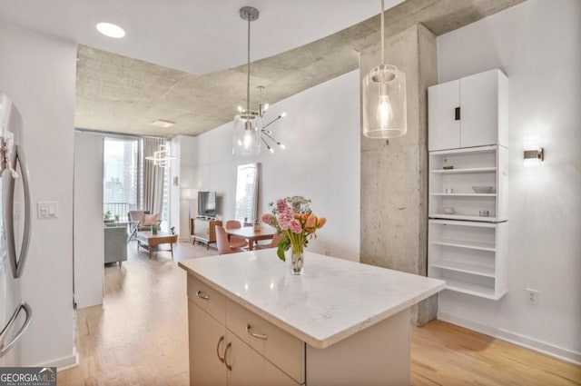 kitchen featuring pendant lighting, freestanding refrigerator, light wood-style flooring, a kitchen island, and open floor plan