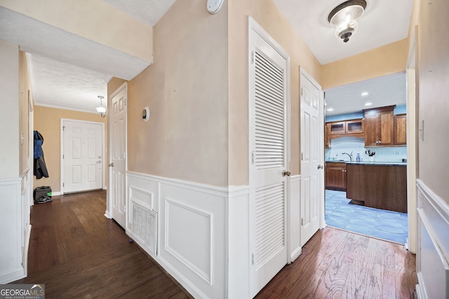 985 Lake Haven Ct, Roswell, GA 30076 - hall with a textured ceiling, a wainscoted wall, a decorative wall, a sink, and wood finished floors