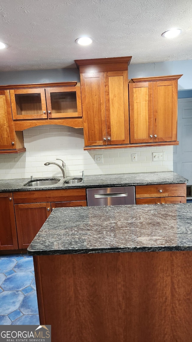 985 Lake Haven Ct, Roswell, GA 30076 - kitchen featuring backsplash, stainless steel dishwasher, a sink, dark stone counters, and brown cabinetry