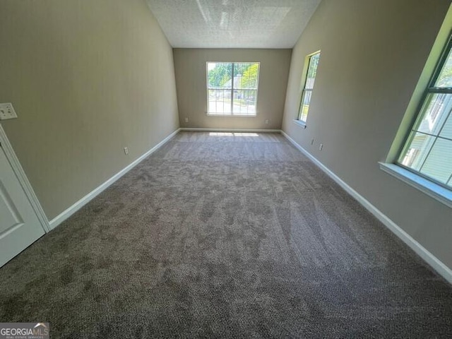 carpeted spare room featuring a textured ceiling and baseboards