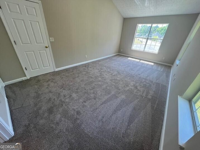 unfurnished room featuring carpet, a textured ceiling, and baseboards