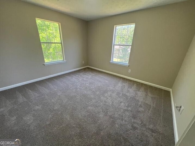 spare room with dark carpet and baseboards