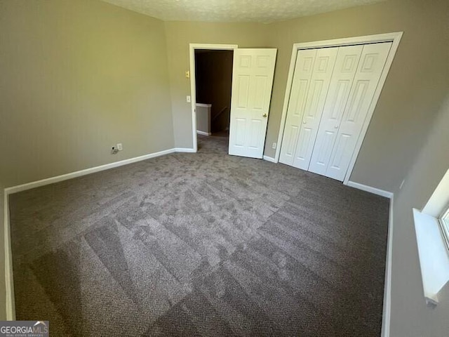 unfurnished bedroom featuring a textured ceiling, a closet, carpet flooring, and baseboards