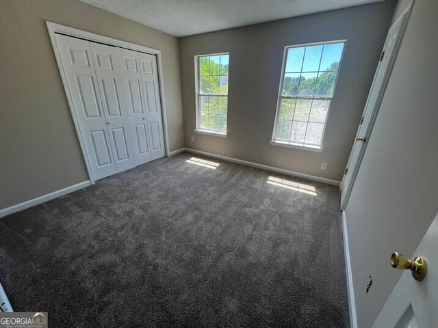 unfurnished bedroom with baseboards, a textured ceiling, carpet floors, and a closet