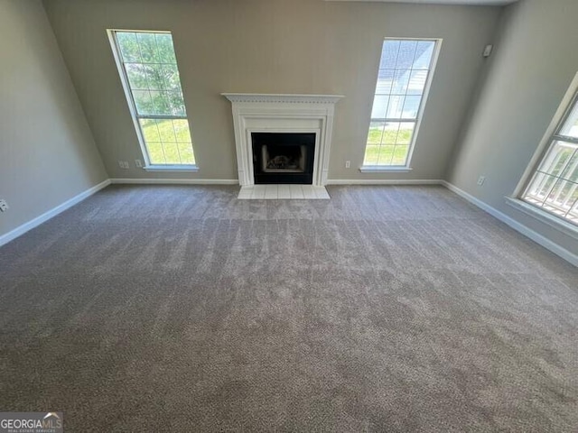 unfurnished living room featuring a fireplace with flush hearth, carpet floors, and baseboards