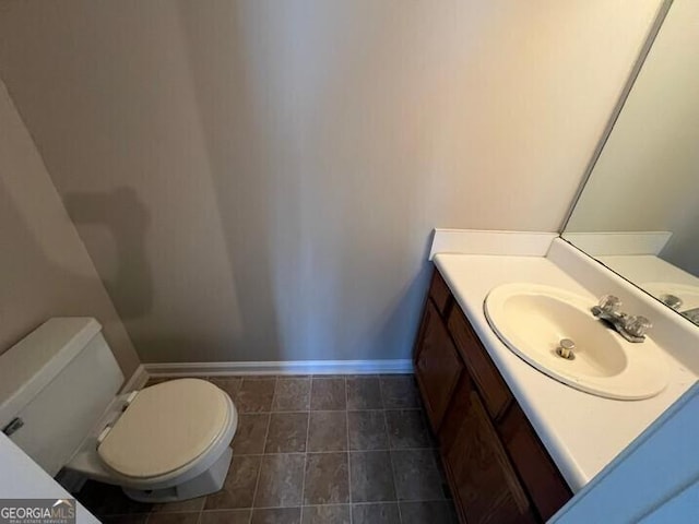 bathroom featuring baseboards, toilet, and vanity