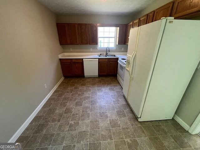kitchen with a sink, baseboards, white appliances, brown cabinets, and light countertops