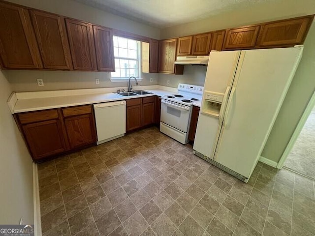 kitchen with under cabinet range hood, light countertops, a sink, white appliances, and brown cabinetry