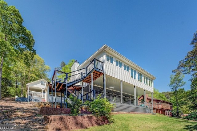 rear view of house with stairway, a chimney, a deck, a yard, and a detached carport