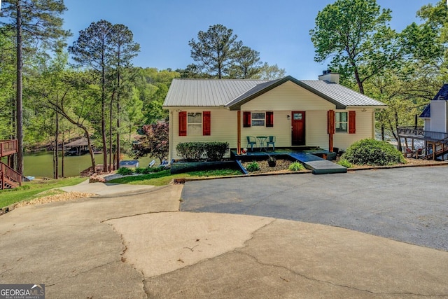 view of front of house with a porch, a chimney, and metal roof