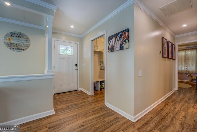 entryway featuring wood finished floors, visible vents, crown molding, and baseboards