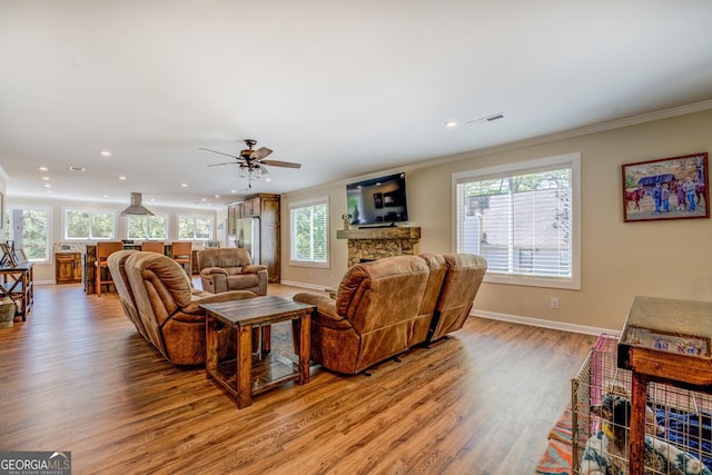 living room with baseboards, a healthy amount of sunlight, light wood-style floors, and crown molding