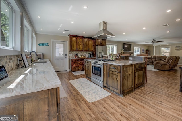 kitchen with light wood-style flooring, visible vents, island range hood, appliances with stainless steel finishes, and ornamental molding