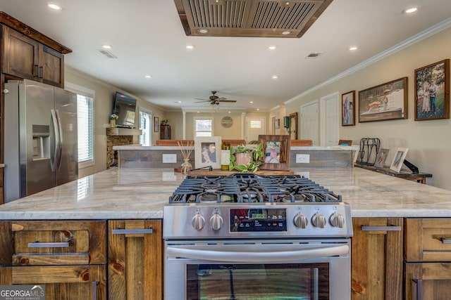 kitchen with crown molding, a wealth of natural light, light stone counters, and stainless steel appliances