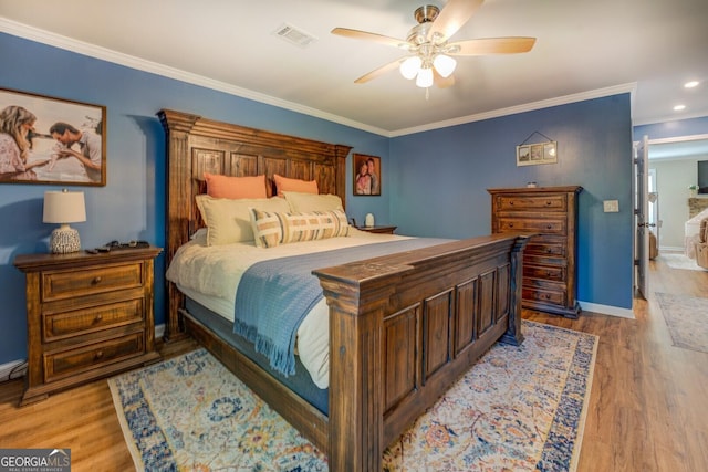 bedroom featuring crown molding, ceiling fan, light wood finished floors, baseboards, and visible vents