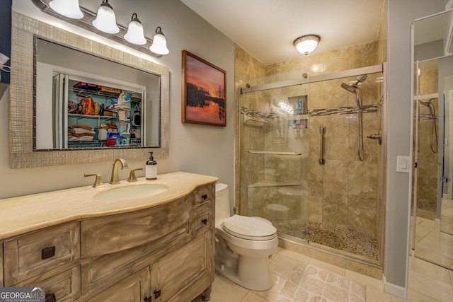 bathroom featuring tile patterned flooring, vanity, toilet, and a stall shower