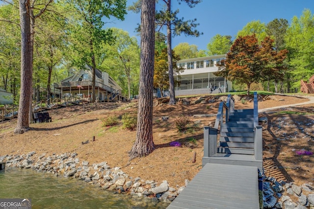 back of property with a water view and stairway