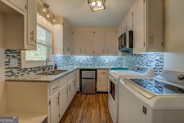 clothes washing area with washer and dryer, wood finished floors, a sink, and laundry area