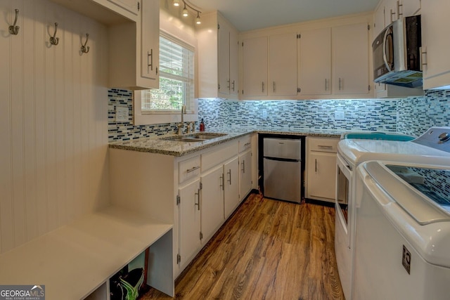 kitchen featuring wood finished floors, a sink, stainless steel microwave, refrigerator, and tasteful backsplash
