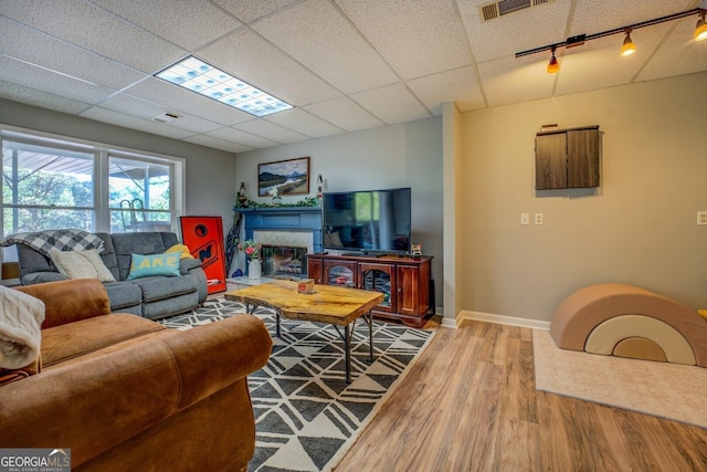 living room with wood finished floors, visible vents, rail lighting, baseboards, and a paneled ceiling