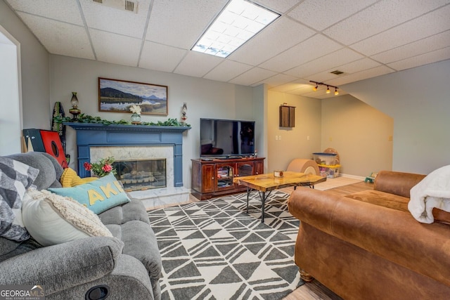 living room with track lighting, visible vents, a fireplace, and a drop ceiling