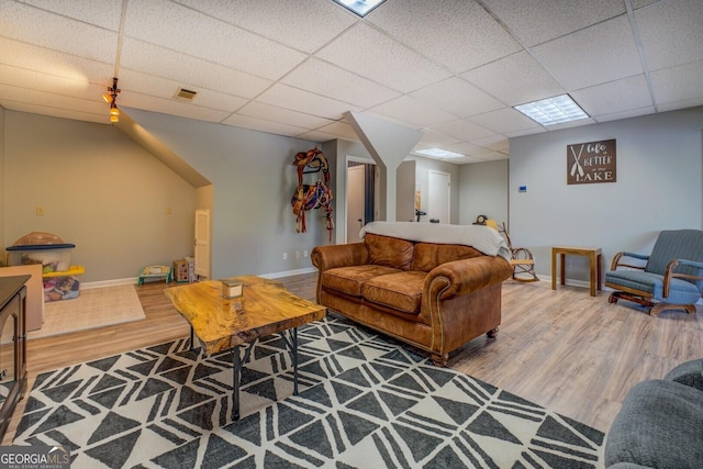 living room with wood finished floors, visible vents, baseboards, and a paneled ceiling