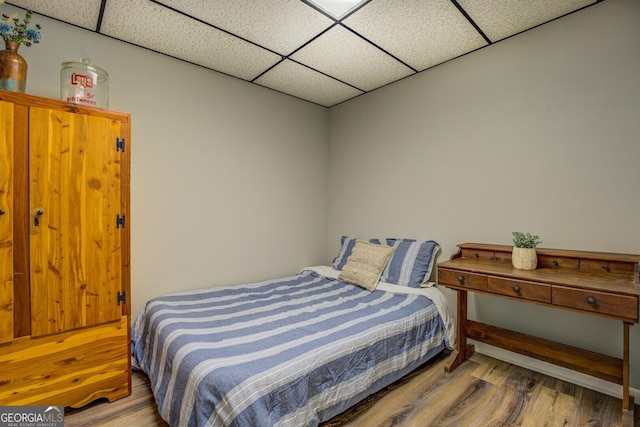bedroom with a paneled ceiling and wood finished floors