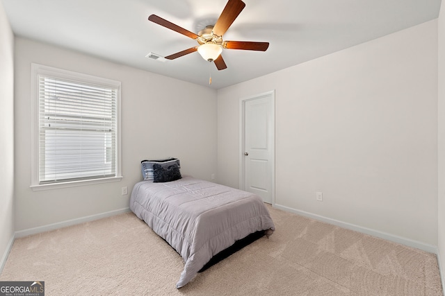 carpeted bedroom featuring a ceiling fan, visible vents, and baseboards