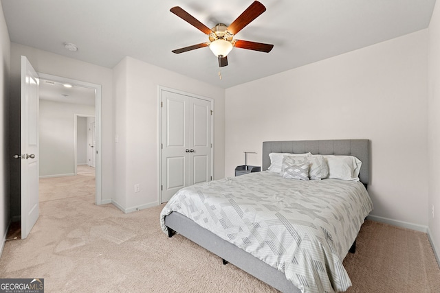 bedroom with a closet, a ceiling fan, light carpet, and baseboards