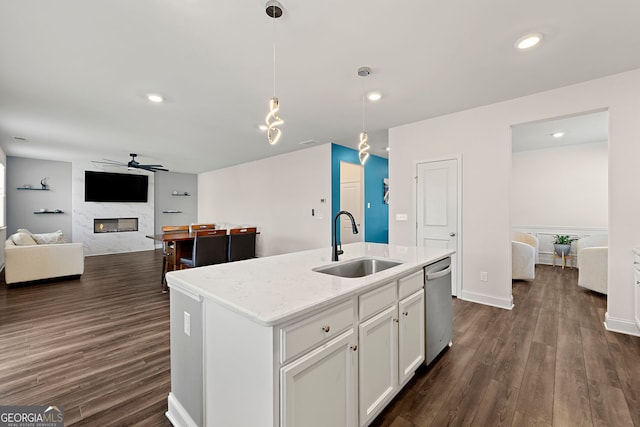 kitchen with stainless steel dishwasher, decorative light fixtures, ceiling fan, a premium fireplace, and a sink