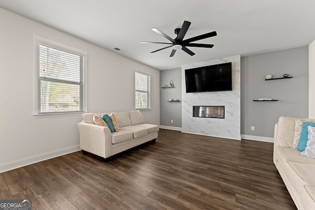 living area with visible vents, baseboards, dark wood-style flooring, a fireplace, and a ceiling fan