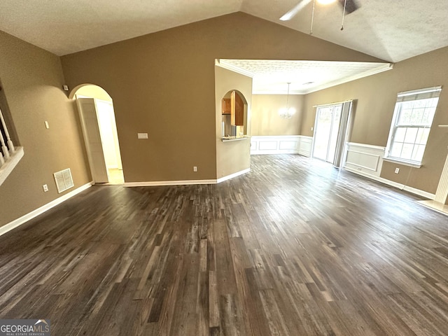 4254 Wood Cove Dr, Snellville, GA 30039 - unfurnished living room with visible vents, arched walkways, dark wood finished floors, ceiling fan with notable chandelier, and lofted ceiling