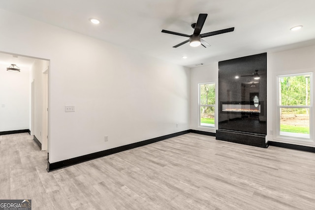 unfurnished living room with baseboards, a ceiling fan, plenty of natural light, and wood finished floors