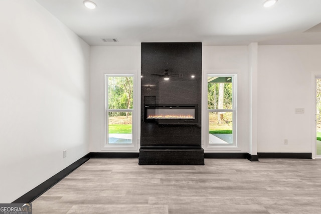 interior space with wood finished floors, baseboards, a large fireplace, and recessed lighting