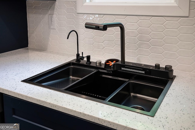 room details with light stone countertops, a sink, and backsplash