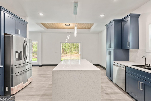 kitchen featuring a tray ceiling, baseboards, light wood finished floors, and stainless steel appliances