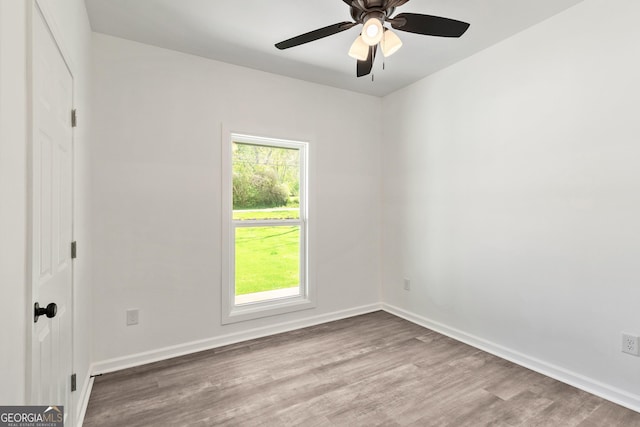 empty room with wood finished floors, baseboards, and a ceiling fan