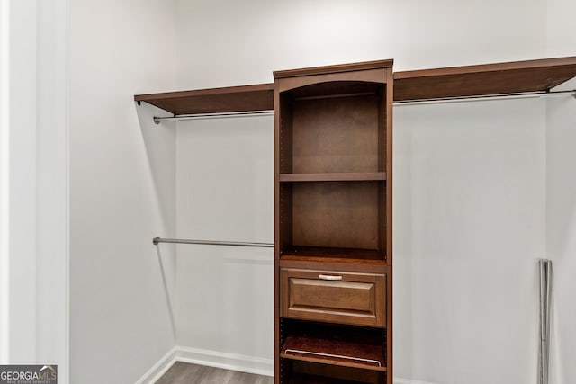 walk in closet with wood finished floors