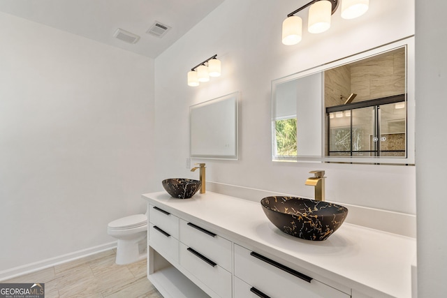 full bath featuring toilet, a shower with shower door, vanity, and visible vents