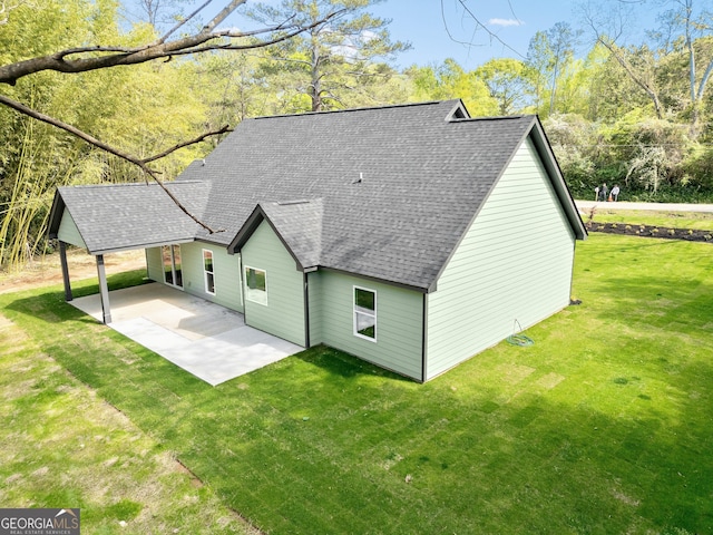 rear view of property with a patio, a shingled roof, and a lawn