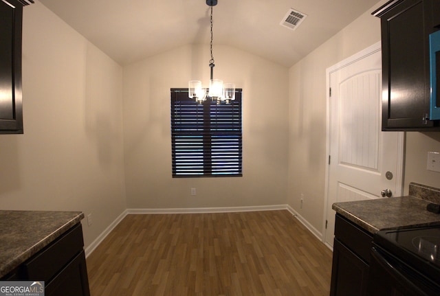 dining space featuring visible vents, a chandelier, wood finished floors, lofted ceiling, and baseboards