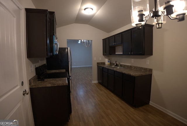 kitchen with an inviting chandelier, a sink, stainless steel microwave, wood finished floors, and vaulted ceiling