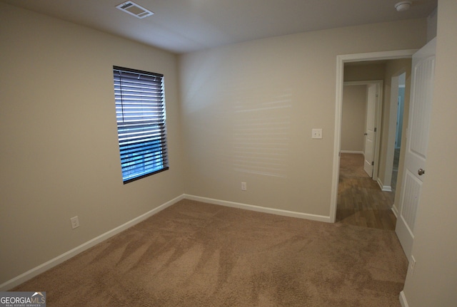 spare room featuring baseboards, visible vents, and carpet floors