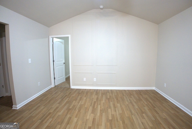 interior space featuring wood finished floors, baseboards, and vaulted ceiling