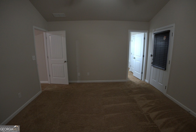 carpeted spare room featuring baseboards and vaulted ceiling
