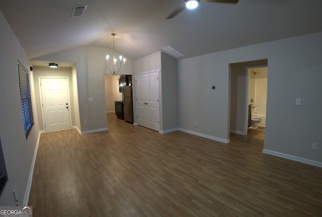 interior space with ceiling fan with notable chandelier, dark wood finished floors, visible vents, lofted ceiling, and baseboards