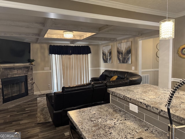 living area with ornamental molding, a stone fireplace, beamed ceiling, dark wood-type flooring, and coffered ceiling