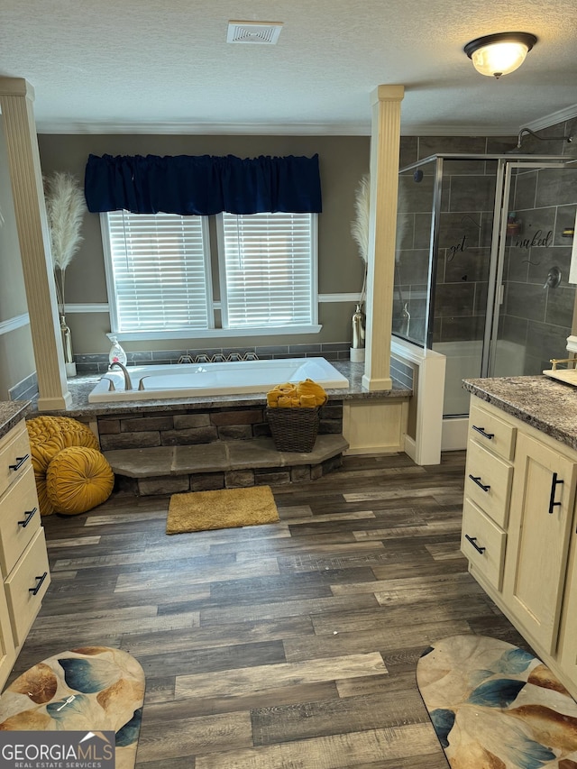 full bathroom with a shower stall, a bath, a textured ceiling, visible vents, and wood finished floors