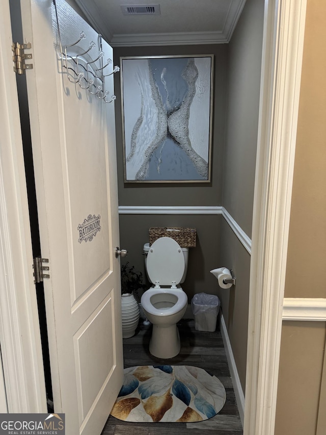 bathroom featuring toilet, baseboards, ornamental molding, and visible vents