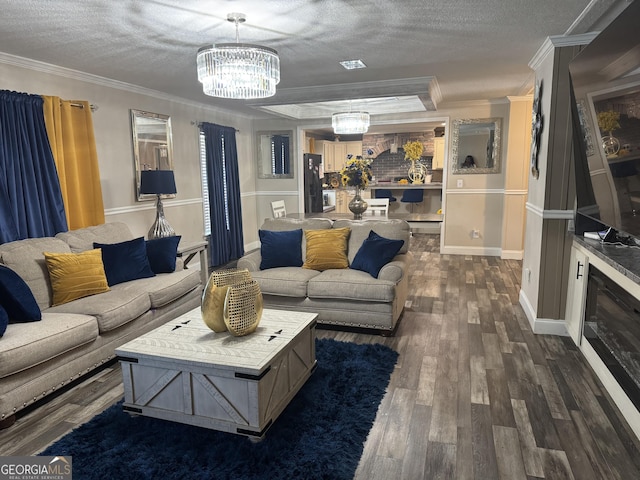 living area featuring crown molding, a textured ceiling, dark wood-style flooring, a notable chandelier, and baseboards